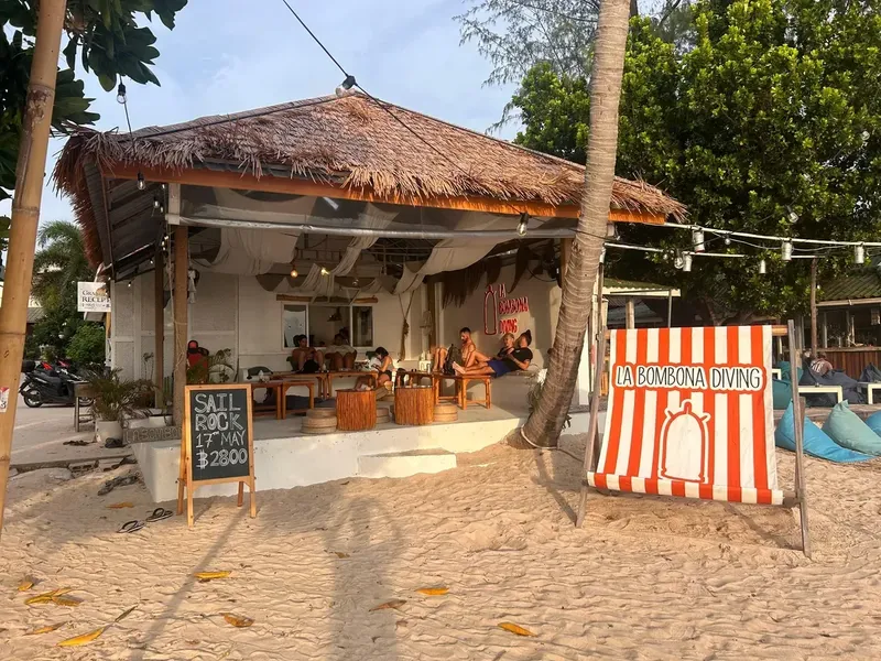 Plage de sable avec un centre de plongée et des personnes assises