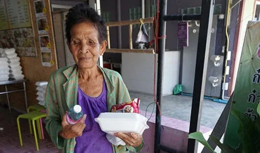 Femme asiatique souriante tenant des plats et une bouteille