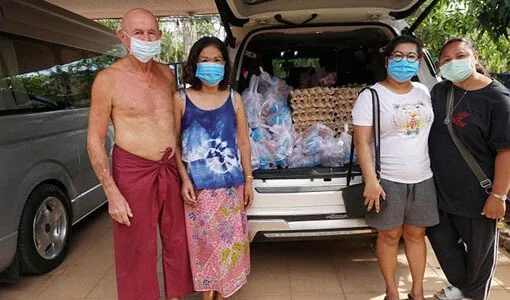 Quatre personnes souriantes, masquées, posent devant un véhicule chargé