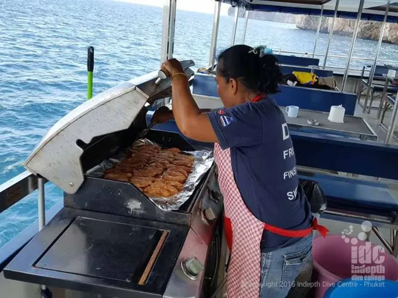 Personne préparant des aliments sur le pont d'un bateau de plongée en mer