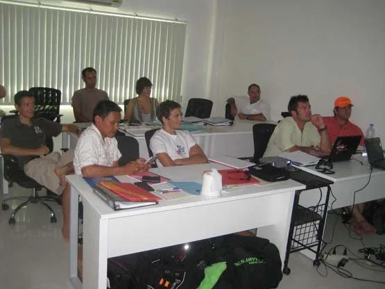 Cours de plongée en salle avec plusieurs personnes et ordinateurs portables