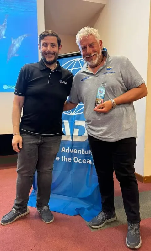 Deux hommes souriants posent devant une bannière de plongée bleue
