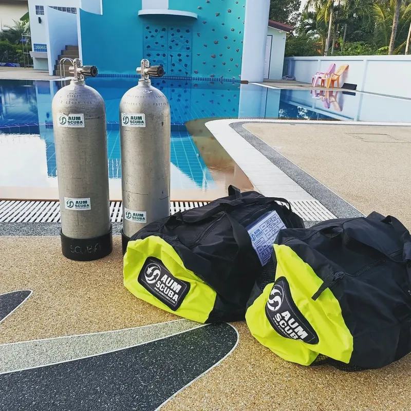 Bouteilles de plongée et gilets stabilisateurs près d'une piscine turquoise