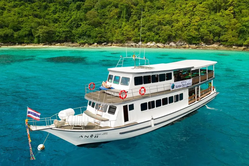 Bateau de plongée blanc et bleu naviguant sur une mer turquoise claire
