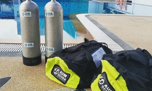 Bouteilles de plongée et sacs noirs et verts au bord d'une piscine