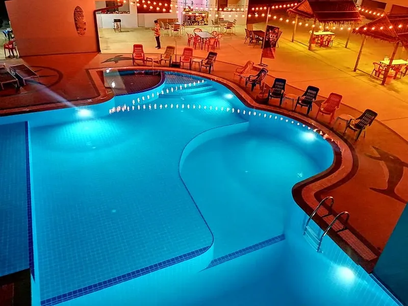Piscine illuminée avec des chaises longues et un espace détente éclairé