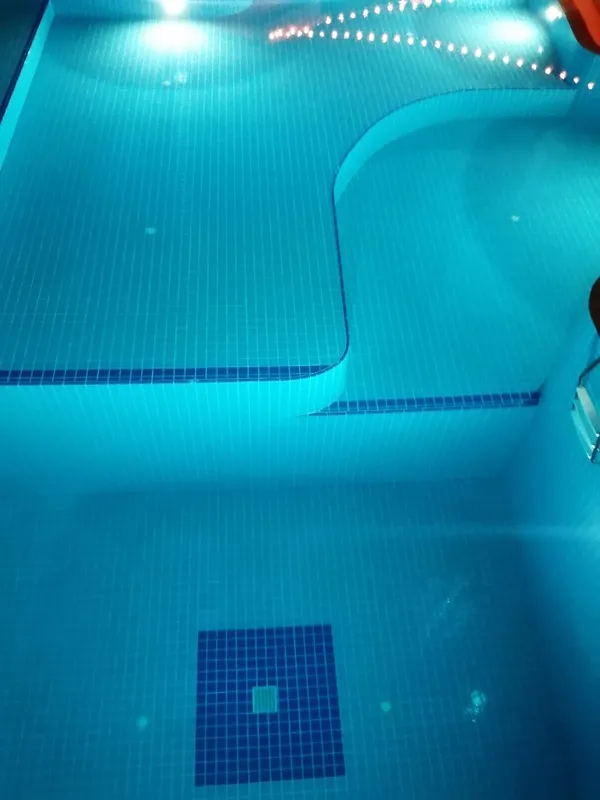 Piscine carree bleue avec des carreaux et un fond clair