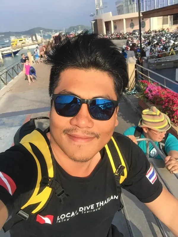 Plongeur souriant avec lunettes de soleil et équipement sur un quai