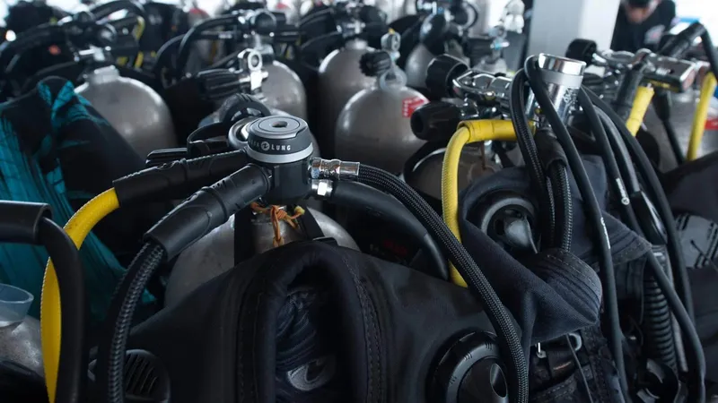 Rangées de bouteilles de plongée avec détendeurs et gilets noirs