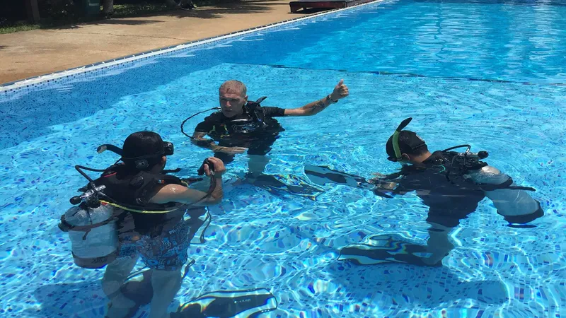 Trois plongeurs en formation dans une piscine, équipement complet visible