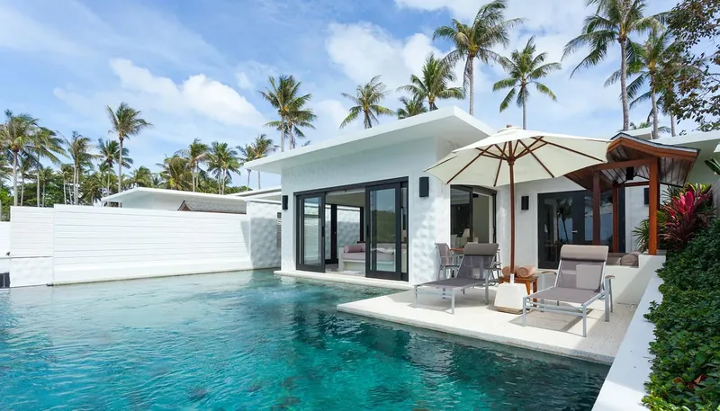 Villa blanche avec piscine, transats et végétation tropicale luxuriante