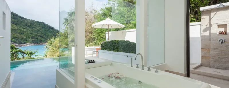 Salle de bain luxueuse avec baignoire et vue sur la mer et végétation