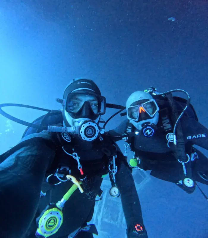 Deux plongeurs souriants avec leur équipement complet sous l'eau