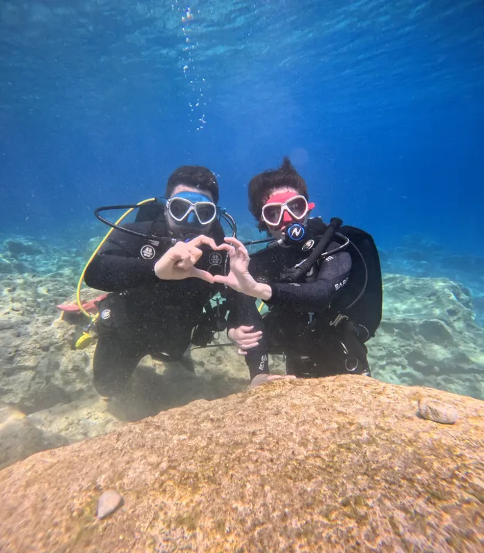 Deux plongeurs souriants forment un cœur avec leurs mains sous l'eau