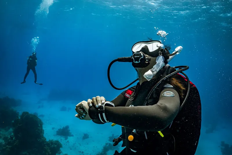 Plongeur vérifiant son ordinateur de plongée en milieu aquatique bleu