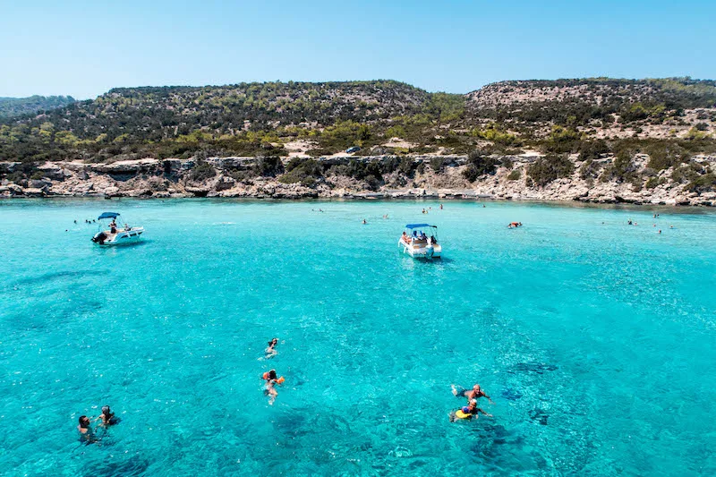 Vue aérienne de baigneurs et de bateaux dans une eau turquoise claire