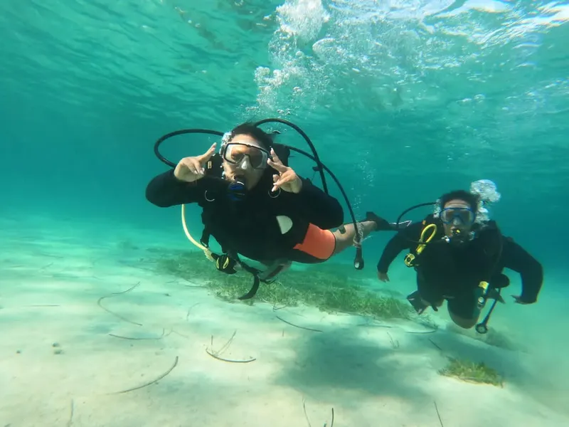 Deux plongeurs souriants font des signes avec leurs mains sous l'eau