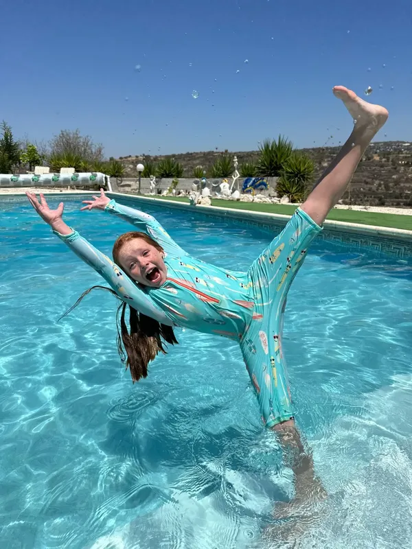 Enfant s'amusant dans l'eau avec une combinaison de plongée turquoise