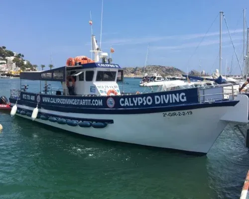Bateau de plongée amarré au port avec le nom du centre visible