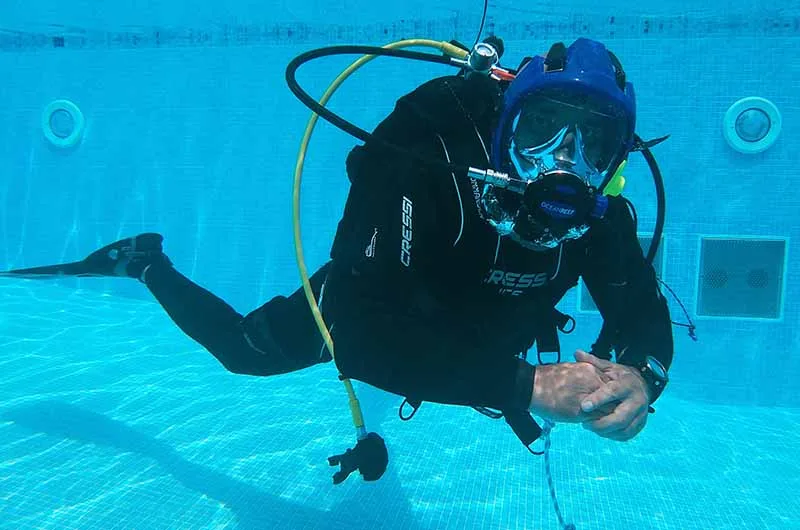 Plongeur en formation dans une piscine, équipé d'un casque intégral