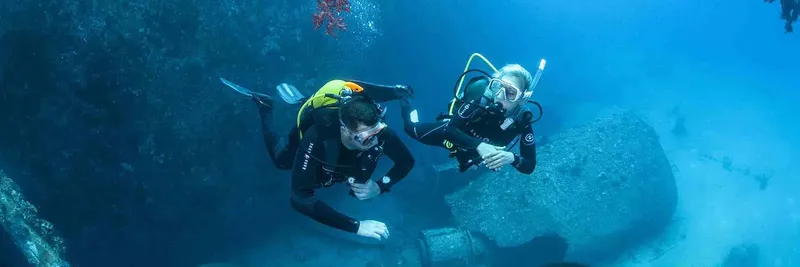 Deux plongeurs explorent un récif rocheux sous l'eau en toute sécurité