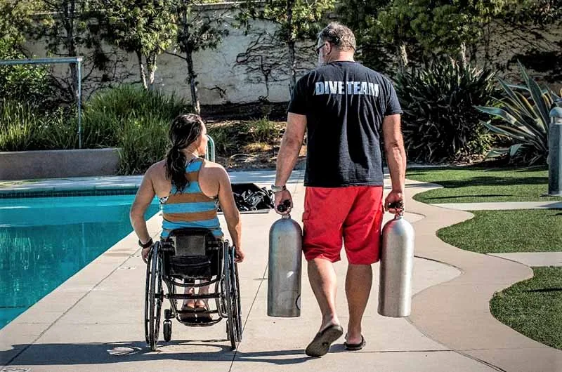 Une personne en fauteuil roulant et un moniteur avec des bouteilles