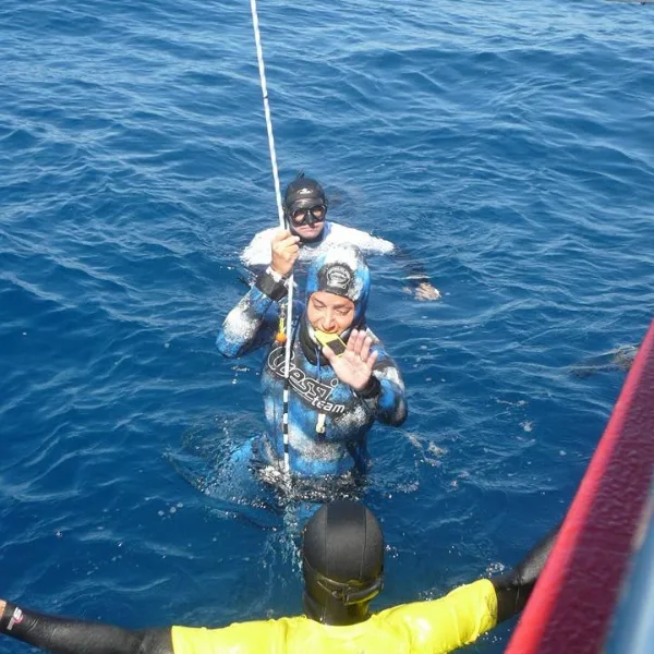 Plongeur en combinaison remonte à bord d'un bateau en mer