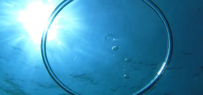 Vue sous-marine avec un cercle métallique et la lumière du soleil