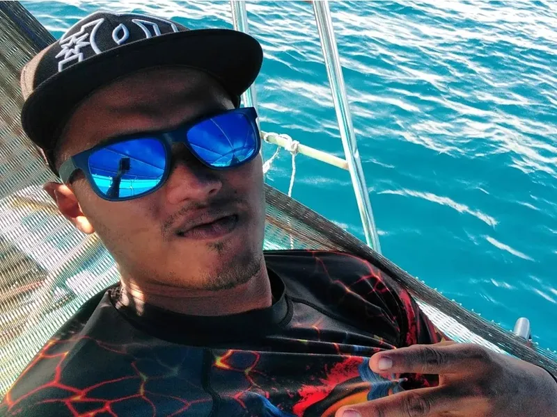 Un homme souriant porte des lunettes de soleil sur un bateau
