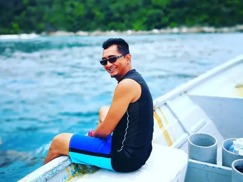 Un homme souriant assis sur un bateau en mer turquoise
