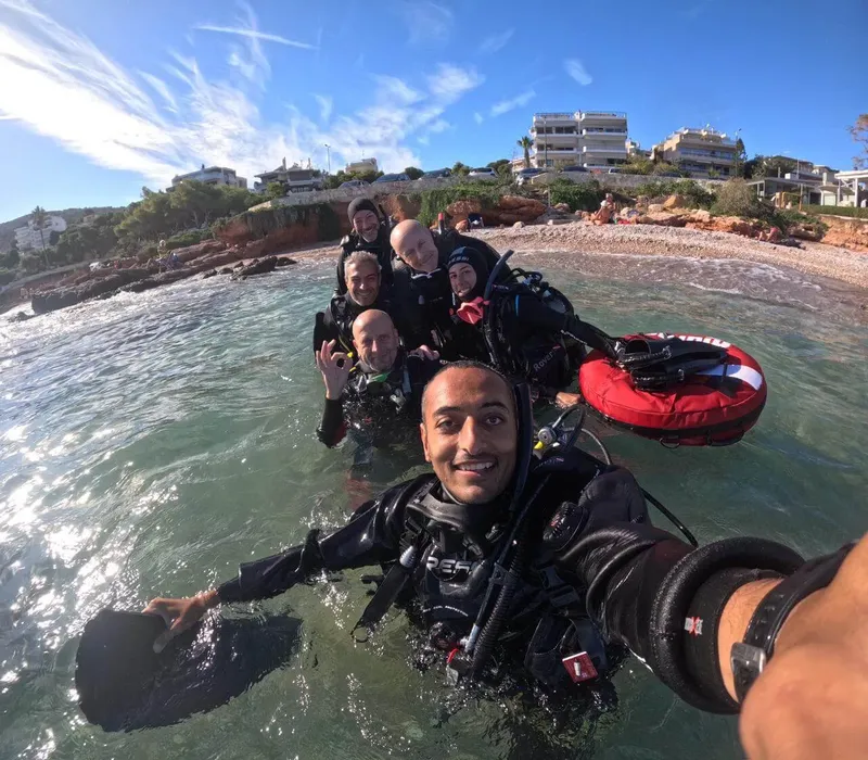 Groupe de plongeurs souriants sortant de l'eau sur une plage ensoleillée