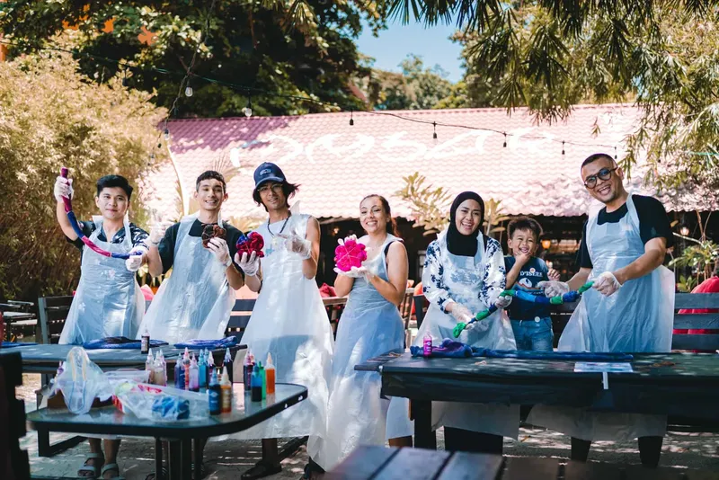 Groupe de personnes souriantes tenant des objets colorés sur une terrasse
