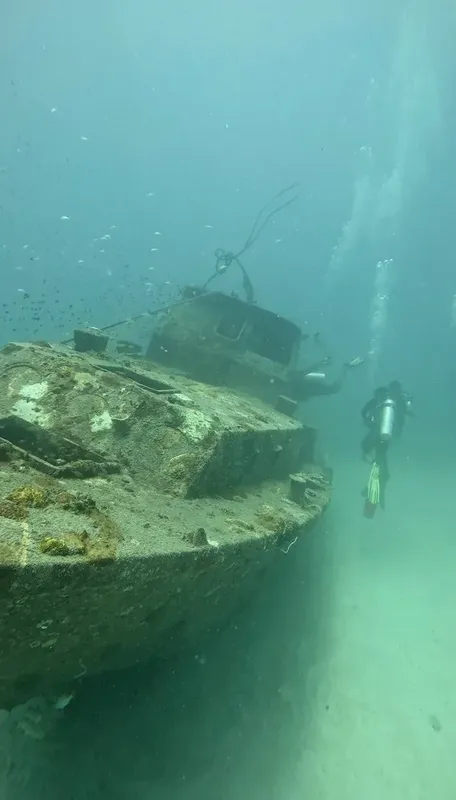 Un plongeur explore l'épave d'un bateau sous l'eau sableux