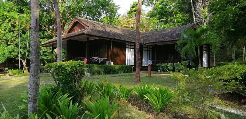 Bâtiment en bois brun avec végétation luxuriante et pelouse soignée