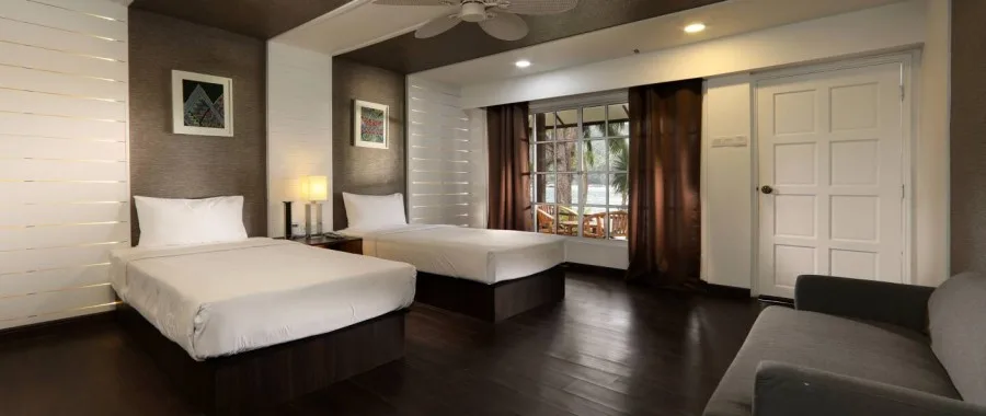 Chambre d'hôtel avec deux lits simples, canapé et décoration sobre