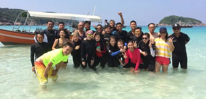 Groupe de plongeurs souriants sur une plage paradisiaque en Asie