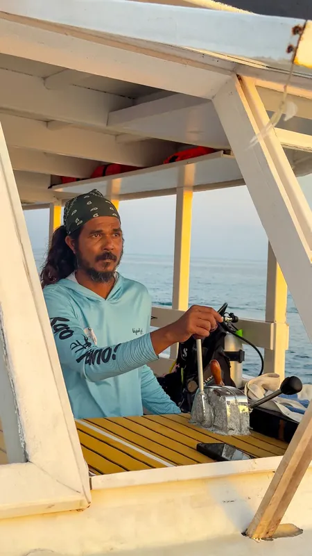 Homme souriant tient la barre d'un bateau de plongée en mer