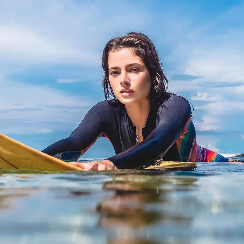 Jeune femme en combinaison de plongée regardant la caméra sur l'eau