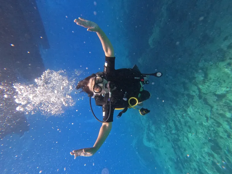 Plongeur en combinaison, équipé, nageant dans une eau bleue claire
