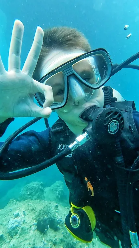 Plongeur souriant faisant un signe de la main sous l'eau