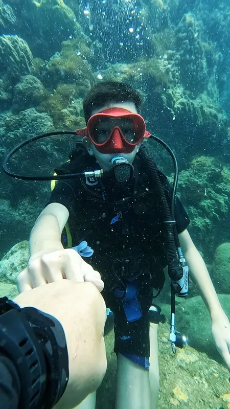 Jeune plongeur souriant avec son équipement, prise de vue sous-marine