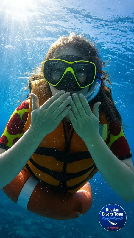 Plongeuse souriante avec masque et gilet, sous l'eau en mer