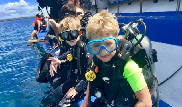 Enfants souriants équipés de masques et gilets sur un bateau de plongée