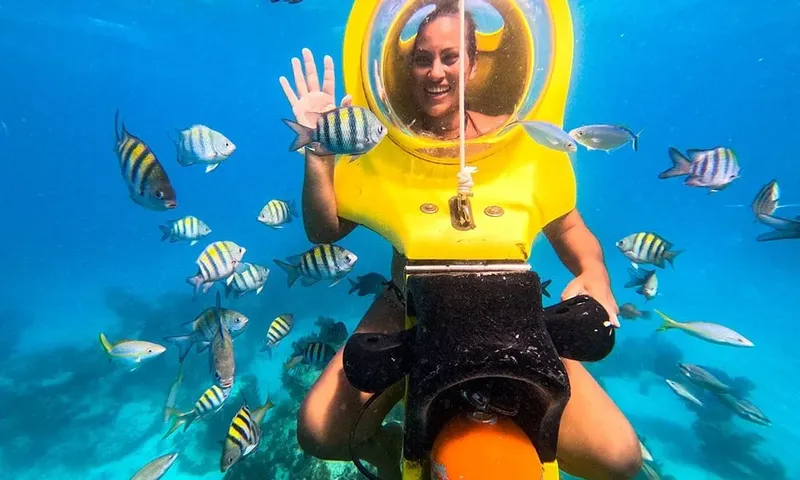 Femme souriante avec casque subaquatique entourée de poissons tropicaux