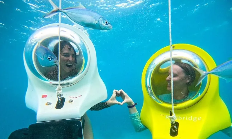 Deux femmes sourient dans des bulles sous-marines avec des poissons