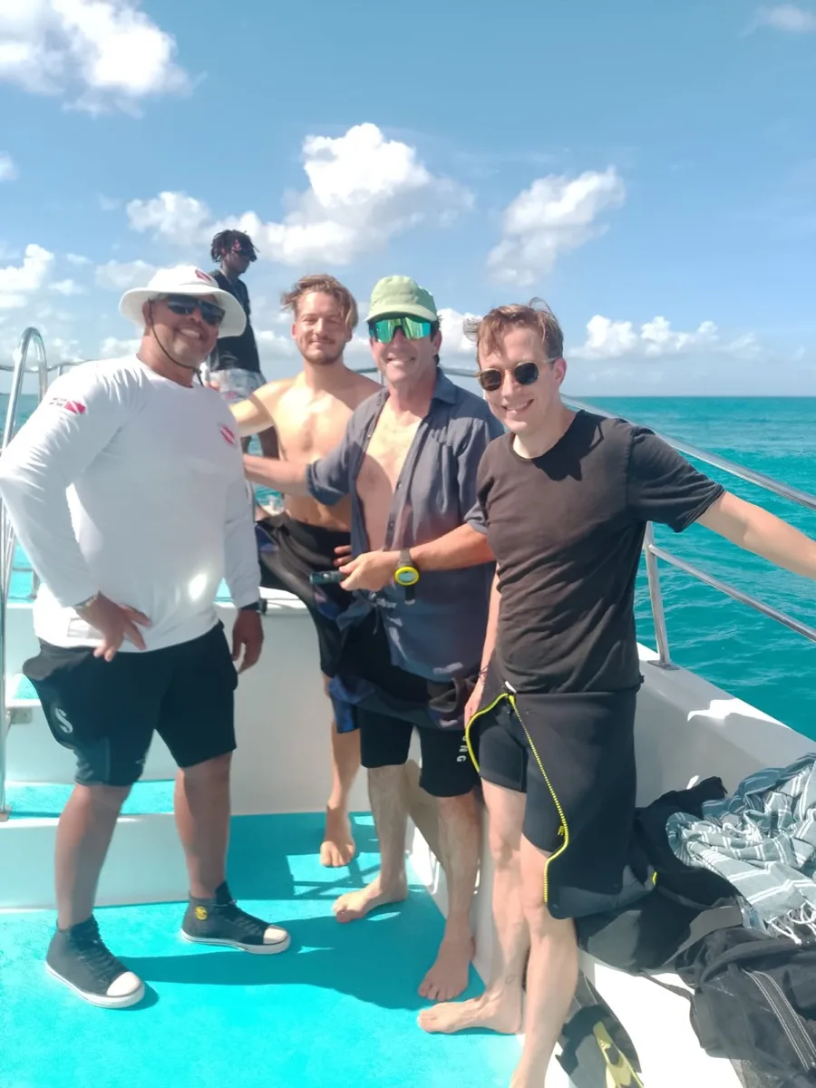 Groupe de plongeurs souriants sur un bateau en mer turquoise