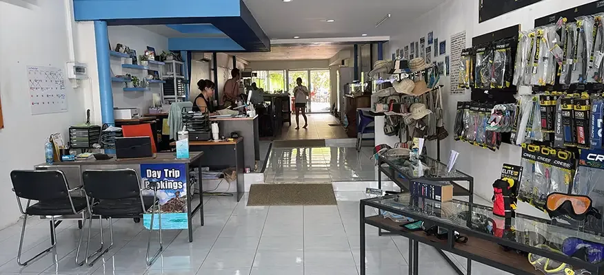Interieur d'un centre de plongee avec comptoir, equipement et clients