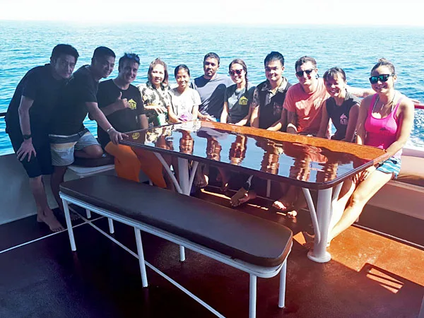 Groupe de personnes souriantes sur un bateau en mer, ambiance conviviale