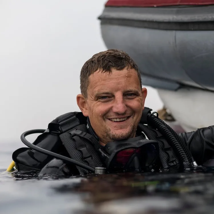 Plongeur souriant émerge de l'eau avec son équipement complet