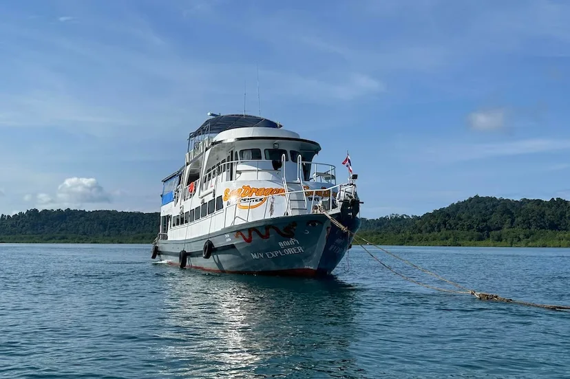 Grand bateau de plongée blanc et bleu amarré dans une baie tropicale